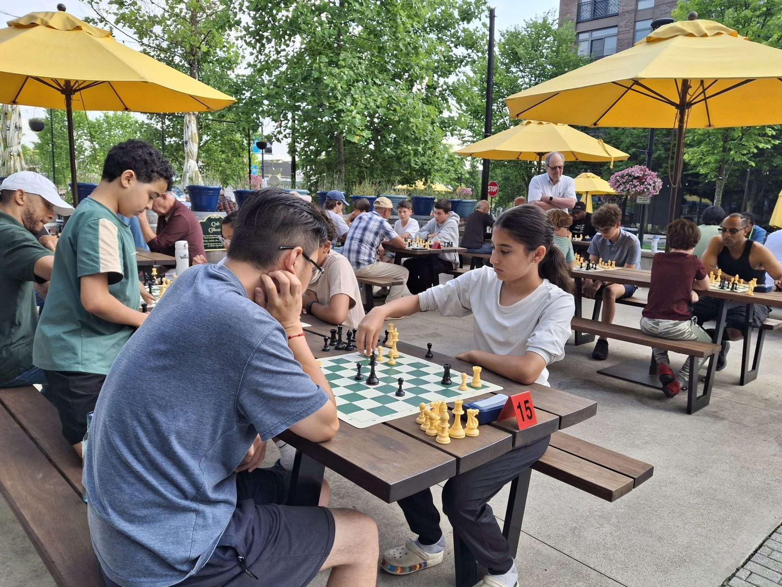 Players at outdoor chess tables during a Strategem Club tournament